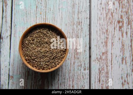 Semi interi di finocchio, finocchio, finocchio, finocchio di Firenze, finocchio o finocchio di testa (Foeniculum vulgare Mill) semi in una ciotola di legno. Su un vecchio tavolo di legno. Foto Stock