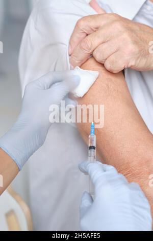 Primo piano del paziente che riceve un'iniezione nel braccio da parte dell'infermiere durante la procedura medica Foto Stock