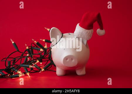 Bianco Piggy banca scatola di denaro coperto in fata luci festive, Natale di risparmio sfondo Foto Stock