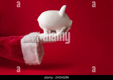 Babbo Natale in possesso di una scatola di denaro Piggy banca di Natale. Concetto di risparmio festivo Foto Stock