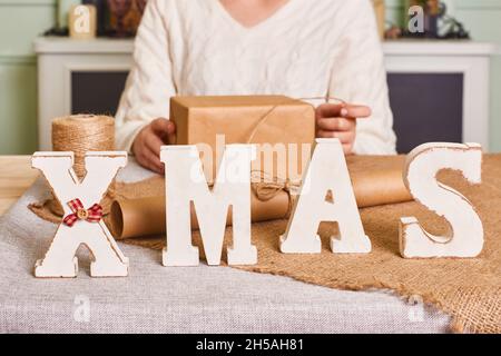 primo piano lettere di natale per la decorazione sul tavolo. Confezione donna con carta ecologica. Felice vacanza presente, sorpresa Foto Stock