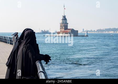 Due donne vestite in abiti musulmani tradizionali hijab nero, burqa e camminare al terrapieno di Istanbul, Turchia Foto Stock