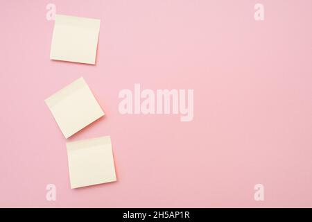 Tre adesivi bianchi per appunti sulla superficie rosa. Vista dall'alto, spazio per il testo. Foto Stock