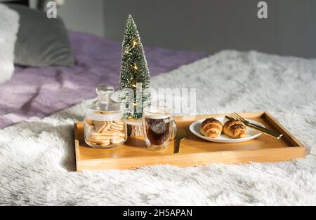 Colazione in camera con tazza di caffè, croissant e biscotti sul vassoio di Natale mattina Foto Stock