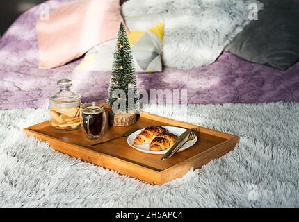 Colazione in camera con tazza di caffè, croissant e biscotti sul vassoio di Natale mattina Foto Stock