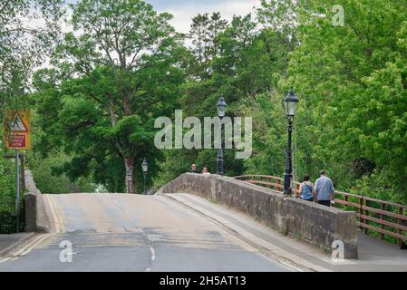 Pateley Bridge, vista delle persone che utilizzano il ponte pedonale che corre lungo il ponte in pietra del XVII secolo a Pateley Bridge a Nidderdale, Yorkshire, Regno Unito Foto Stock