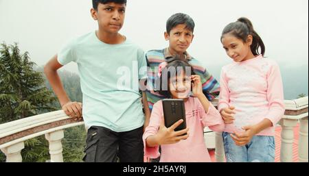 Quattro piccoli fratelli indiani che prendono un selfie all'aperto in una giornata di sole Foto Stock