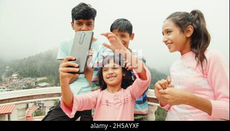 Quattro piccoli fratelli indiani che prendono un selfie all'aperto in una giornata di sole Foto Stock