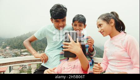 Quattro piccoli fratelli indiani che prendono un selfie all'aperto in una giornata di sole Foto Stock