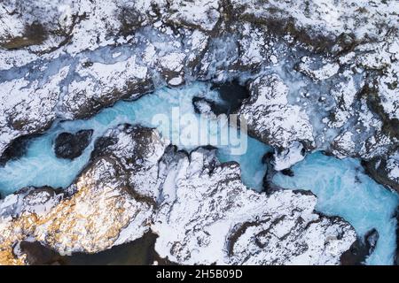 Vista aerea, girato dritto verso il basso, del fiume veloce Hvita tra rocce laviche coperte di neve, appena prima della cascata Barnafoss, Vesturland Foto Stock