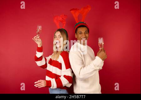 Giovani in cappelli con corna con bicchieri di champagne Foto Stock