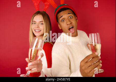 Giovani in cappelli con corna con bicchieri di champagne Foto Stock