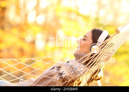 Ritratto laterale di una donna felice che ama ascoltare musica in autunno Foto Stock