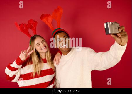 Una giovane coppia felice in cappelli cornati facendo selfie Foto Stock