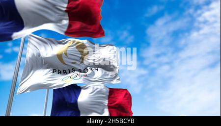 Tokyo, Giappone, luglio 2021: Parigi 24 bandiera olimpica che sventola nel vento tra due bandiere francesi. Le olimpiadi estive di Parigi 2024 sono in programma dal 26 luglio Foto Stock