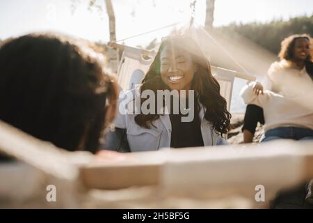Felice giovane donna che trascorre tempo libero con gli amici a Lakeshore in giornata di sole Foto Stock