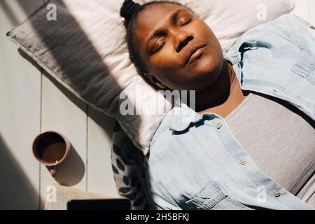 Direttamente sopra la vista della donna che giace con gli occhi chiusi alla luce del sole Foto Stock