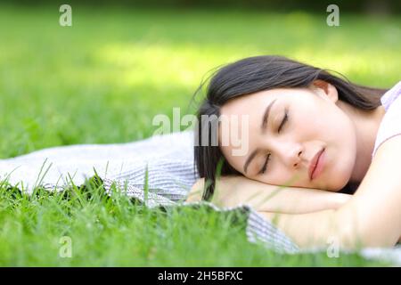 Donna asiatica che dorme sull'erba in un parco Foto Stock