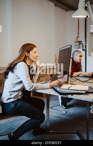 Programmatore femmina maturo che codifica su computer e laptop in azienda startup Foto Stock