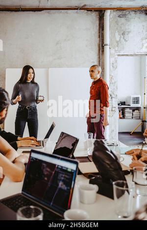 Giovane imprenditrice femminile che presenta ai colleghi in carica Foto Stock