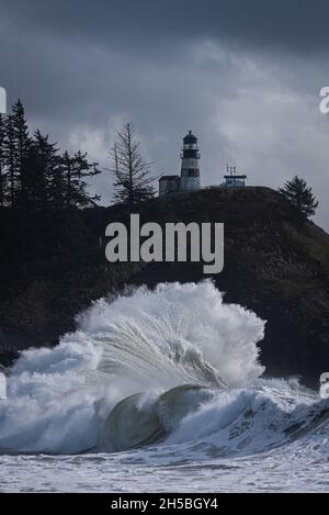 Grande onda dell'oceano che si schiantava sotto la casa di luce durante la tempesta di marea del re di inverno sulla costa pacifica, stato di Washington Foto Stock