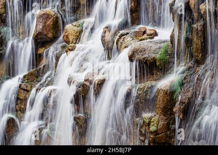 Potente cascata con molti ruscelli d'acqua che corrono intorno alle rocce e alle pietre, un primo piano Foto Stock