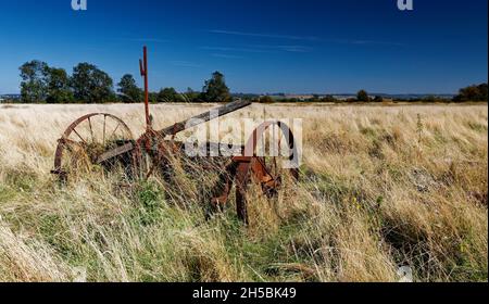 Rusty Hay Maker ha lasciato in un campo Foto Stock