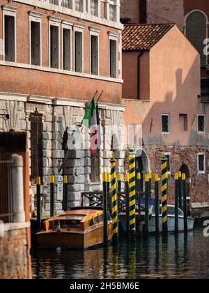 Venezia, Italia - 31 ottobre 2021: Pali gialli a strisce blu di fronte alla vecchia casa di Venezia (Italia), taxi boat Foto Stock