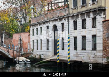 Venezia, Italia - 31 ottobre 2021: Pali gialli a strisce blu di fronte alla vecchia casa bianca di Venezia (Italia) Foto Stock