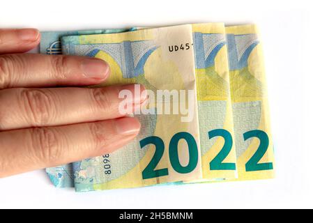 2022 scritto con banconote in euro in una mano isolato su sfondo bianco, nuovo anno saluti concetto di denaro Foto Stock