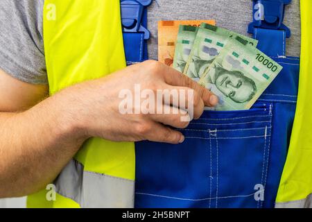 Lavoratore contando i suoi guadagni, il denaro del Costa Rica, concetto di salari e costi del lavoro nell'industria Foto Stock