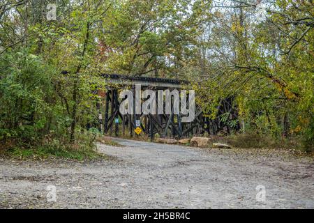 Un traliccio ferroviario in legno ancora in uso lungo una strada di ritorno con una strada privata che passa sotto nel Tennessee rurale circondato da alberi in autunno Foto Stock