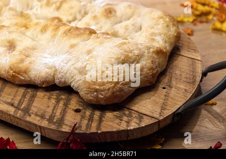 Una croccante focaccia italiana su un tagliere in legno Foto Stock