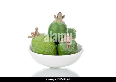 Diversi frutti di feijoa dolci maturi con un piatto di ceramica, primo piano, isolato su bianco. Foto Stock