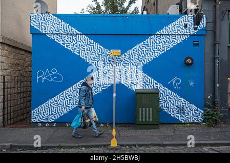 Uomo con le borse portaerei di shopping passeggiando lungo la strada di Sestyre Scozzese a Leith, Edimburgo, Scozia, Regno Unito. Foto Stock