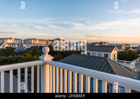 Tramonto a Seaside, Florida Golfo del Messico, vista dal tetto in legno terrazza edificio balcone con case paesaggio urbano e ringhiera bianca balaustra palla t Foto Stock