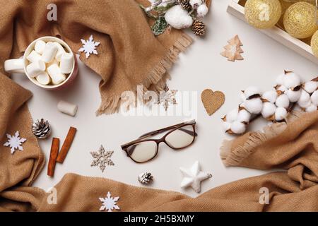 Sciarpa in cashmere beige con una tazza di calici marshmallow su sfondo grigio chiaro. Concetto di comfort invernale. Vista dall'alto Flat Lay. Foto Stock