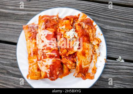 Piano sopra la vista del piatto con mucchio di enchiladas cibo messicano fatto in casa con salsa di pomodoro, tortilla e formaggio fuso Foto Stock