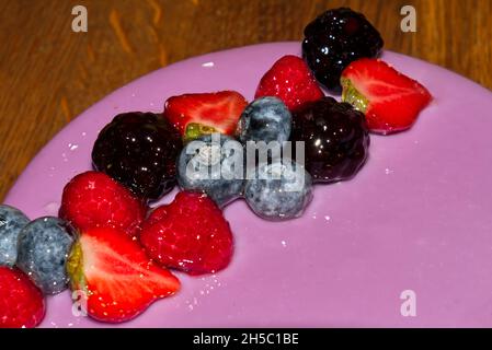 primo piano di una torta di compleanno con panna rosa e bacche fresche Foto Stock