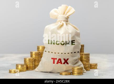Ricevute fiscali. Tasse elevate. Il sacchetto di soldi e monete è diviso in metà per le tasse ed il reddito. Foto Stock