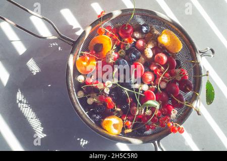 Vari bacche in un colino metallico. Uve secche di Corinto, ciliegie e albicocche Foto Stock