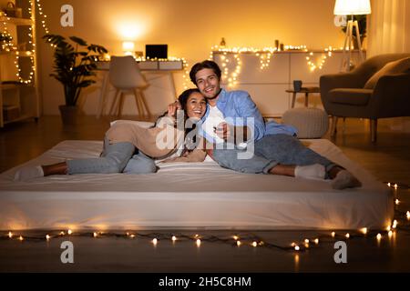 La coppia sta godendo il film sulla TV sdraiato sul materasso a casa Foto Stock
