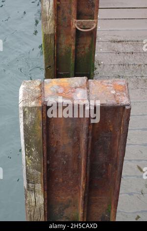 Primo piano di barra di protezione in legno e metallo vicino al percorso in legno parzialmente in acqua Foto Stock