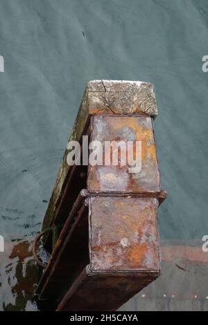 Primo piano di barra di protezione in legno e metallo vicino al percorso in legno parzialmente in acqua Foto Stock