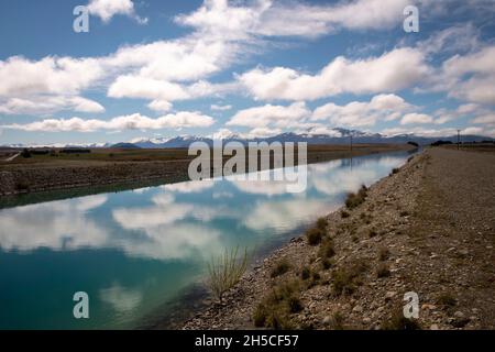 Nuvole bianche nel cielo blu, riflesse in Tekapo Canal, MacKenzie Country, Canterbury, South Island, Nuova Zelanda Foto Stock