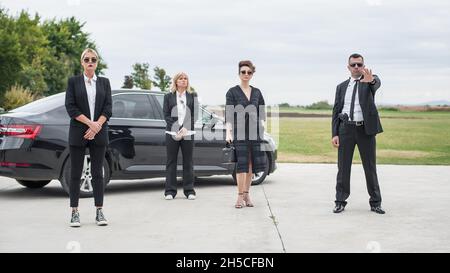 Un team professionale di guardie del corpo maschili e femminili protegge la famosa persona pubblica VIP. Chiudere la protezione di sicurezza. Agente di polizia in nero civile Foto Stock