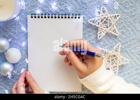 Le mani delle donne sopra un foglio bianco del taccuino, tengono una penna blu della fontana Foto Stock