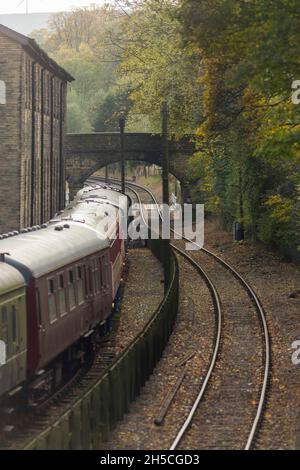 Haworth è una destinazione turistica conosciuta per la sua associazione con le sorelle Brontë e il patrimonio conservato Keighley e Worth Valley Railway. Il villaggio è situato all'interno delle colline Pennine del West Yorkshire, nel Regno Unito ed è famoso per la sua ripida strada principale acciottolata. Foto Stock