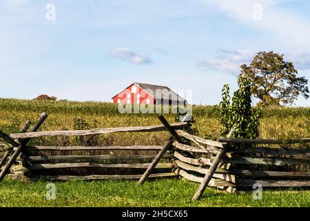 Una recinzione in legno con il fienile Klingle Farm in lontananza al Gettysburg National Military Park, Gettysburg, Pennsylvania, USA Foto Stock