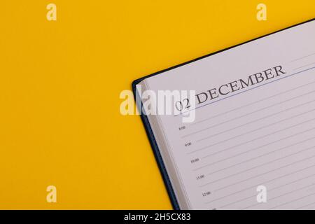 Blocco note o agenda con la data esatta su sfondo giallo. Calendario del 2 dicembre - ora invernale. Spazio per il testo. Foto Stock